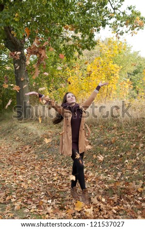 cheerful young woman throws with leaves