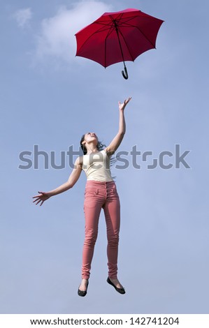 young woman jumping with red umbrella