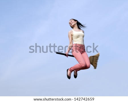happy young woman flying with a broom