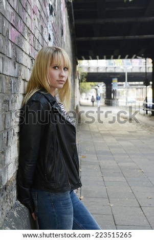 young woman with leather jacket under old bridge