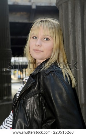 smiling young woman with leather jacket under old bridge