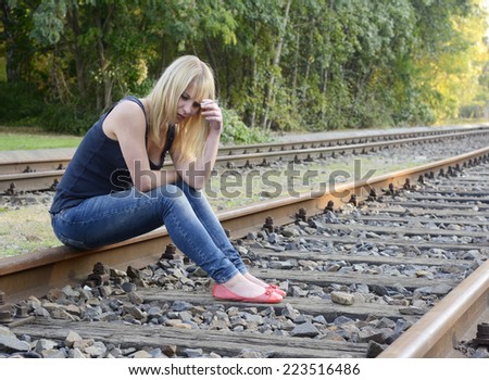 frustrated young woman with cigarette sitting on rail track