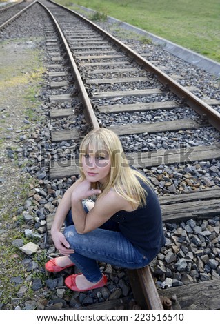 depressed young woman sitting on rail track