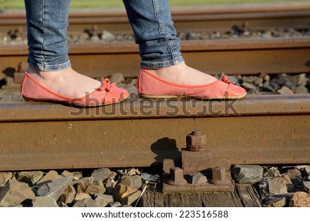 young woman balancing on rail track, detail