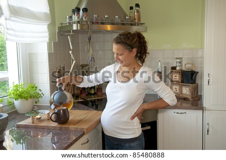 pregnant young woman pouring tea