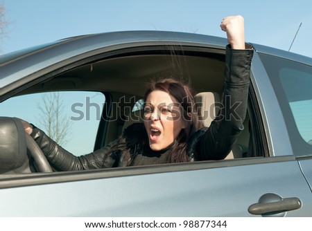 angry young woman in the car shows the fist