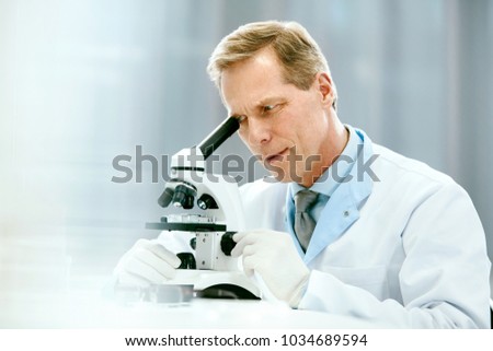 Clinical Test. Scientist With Microscope In Laboratory. Portrait Of Mature Man In Lab Coat Researching, Working At Workplace In Light Modern Medical Laboratory. Science And Medicine. High Quality