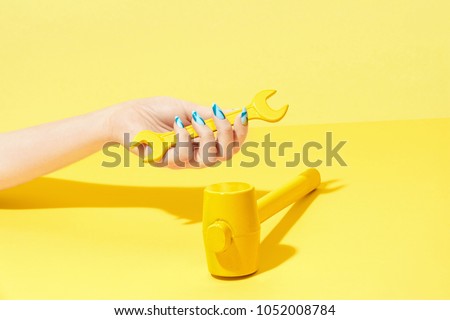 Nails Design. Hand With Colorful Nails On Yellow Background. Close Up Of Female Hands With Beauty Bright Geometric Manicure And Colored Hammer On Yellow Background. High Quality Image.
