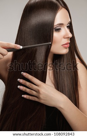 Brown Hair. Beautiful Woman combs her Healthy Long Hairr. High quality image.