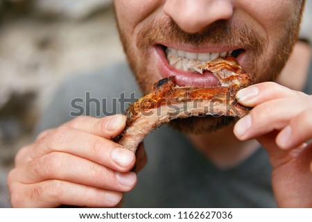 People Eat Food. Man Eating Barbecue Ribs In Grill Bar Closeup. Male Eating Spareribs In Steak House. High Resolution
