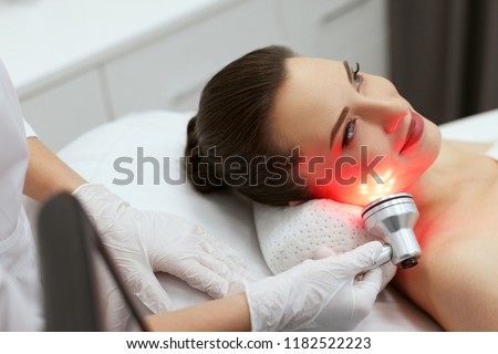 Red Led Light Treatment. Woman Doing Facial Skin Therapy