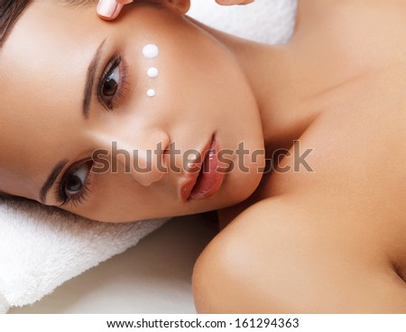Close-Up Of A Young Woman Getting Spa Treatment. Cosmetic Cream On A Cheek. Skin Care