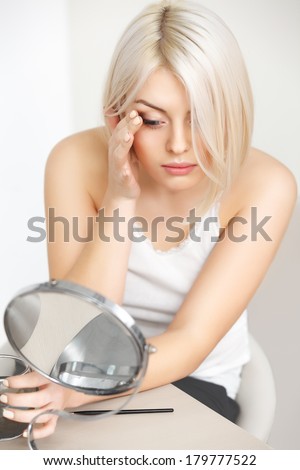 Makeup Applying. Beautiful Woman Looking at Her Face in the Mirror. Daily Morning Makeup