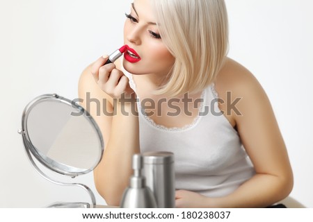 Woman applies red lipstick  Red Lips and Blond Hair. Daily Make-up