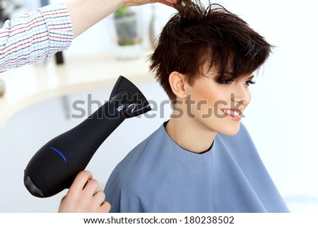 Hairdresser Using Dryer on Woman Wet Hair. Brunette with Short Hair in Hair Salon.