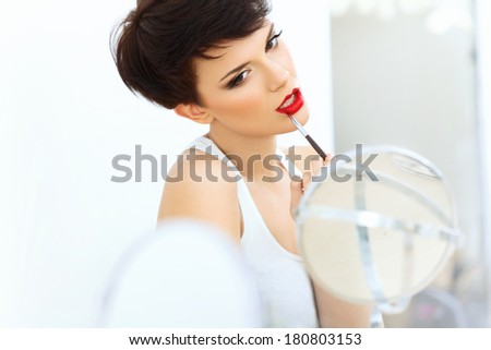 Beautiful Brunette applies lipstick.  Lipgloss and Brush. Red lips Makeup