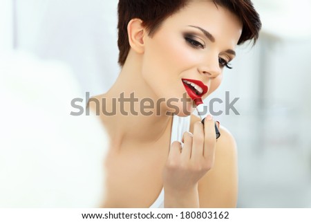 Beautiful Brunette applies lipstick.  Lipgloss and Brush. Red lips Makeup
