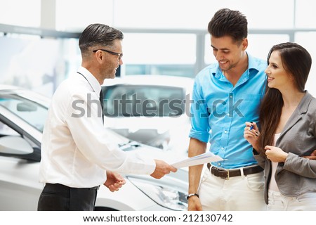 Young Couple Signing a Contract in Car Showroom.