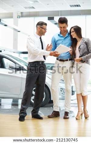 Young Couple Signing a Contract in Car Showroom.