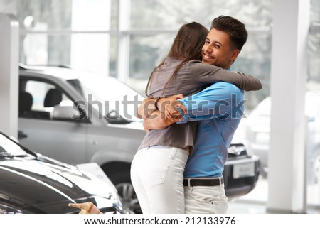 Young Couple Celebrating Purchase of a car In Car Showroom