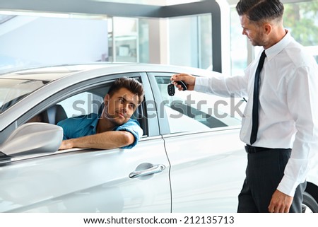 Car Salesman Handing over new Car Key to Customer at Showroom