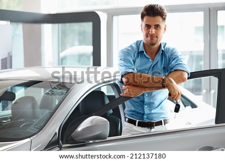 Car Showroom. Happy Man With Keys To The Car Of His Dreams.