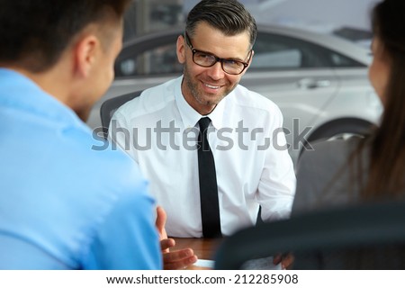 Couple Signing Salesman Contract. Car Showroom