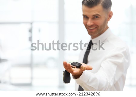 Car Salesman Giving Key of New Car at Showroom