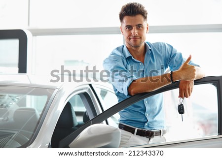 Car Showroom. Happy Man With Keys To The Car Of His Dreams.