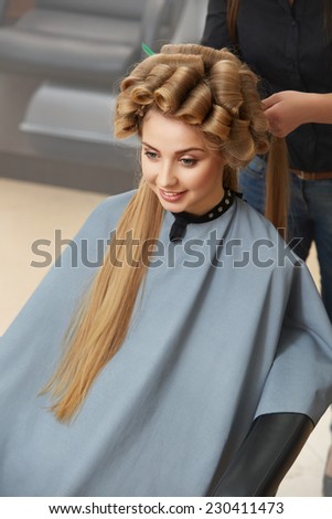 Hairdresser doing hairstyle for young beautiful woman