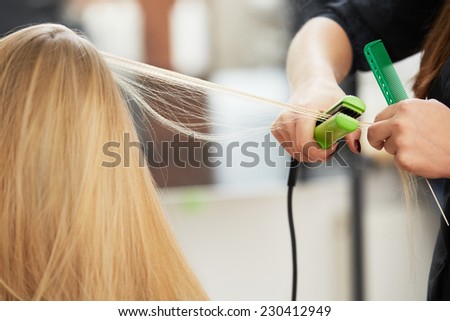 Hairdresser curling hair with straightener