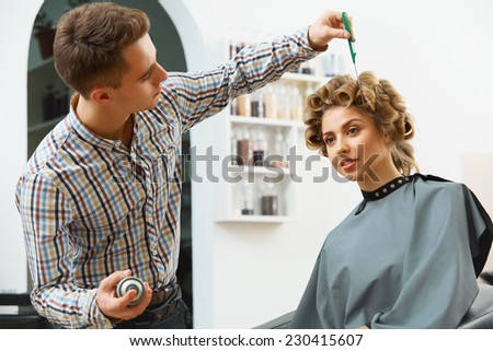 Hairdresser doing hairstyle for young beautiful woman
