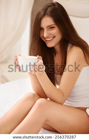 Coffee. Beautiful Girl Drinks Tea or Coffee Sitting on Bed