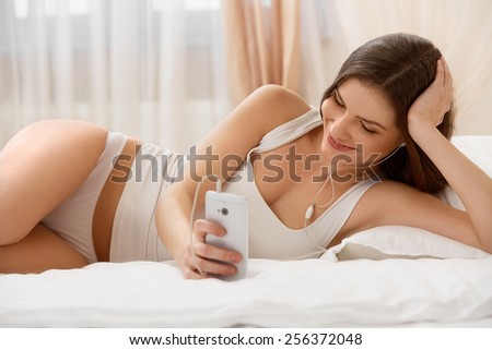 Beautiful Woman Listens a Music lying on the bed