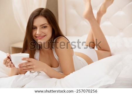 Woman Holds Cup of Tea Lying on the Bed.