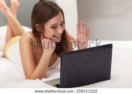 Woman lying in her bedroom using a laptop. Video Call