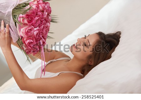 Woman Smelling a Flowers While Lying on Her Bed
