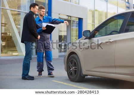 Mechanic and Customer Discussing Problem With Car. Auto Repair Shop