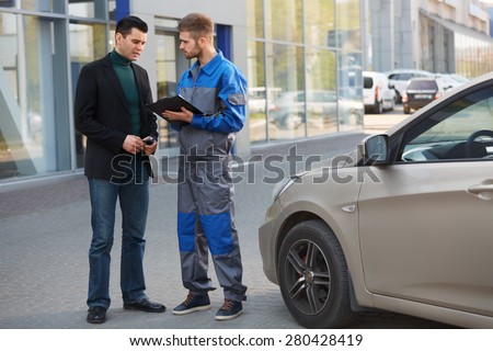 Mechanic and Customer Discussing Problem With Car. Auto Repair Shop