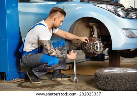 Car Mechanic Changing Tire in Professional Car Repair Service