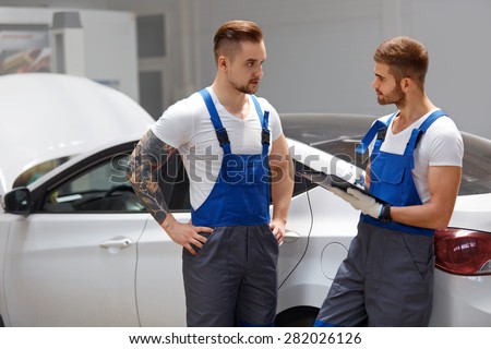 Mechanics Team Talking About a Car Problem. Auto Repair Garage