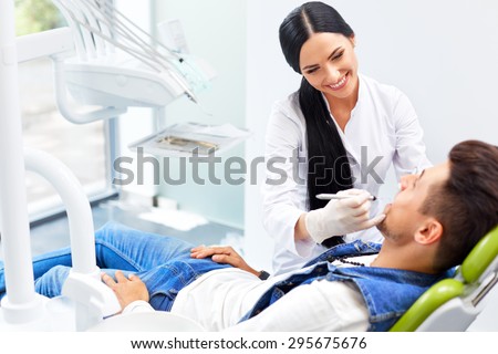 Famele dentist and man in dentists office.  Dentist and Patient