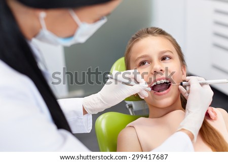 Teeth checkup at dentist\'s office. Dentist examining girls teeth in the dentists chair
