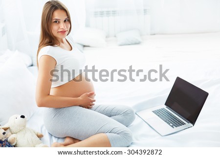 Pregnant Woman With Laptop Computer. Beautiful Pregnant Woman Working on Laptop at Home