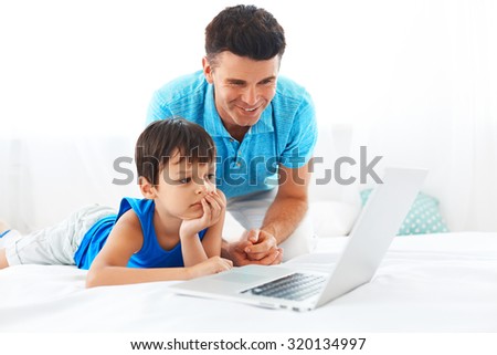 Father and son having fun using laptop. Happy family spending weekend together.