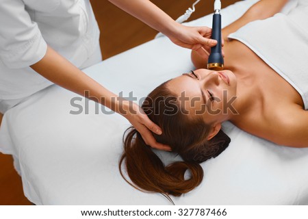 Face skin care. Beautiful young healthy caucasian woman lies on a table in a medical cosmetology spa salon getting facial skin care treatment. Ultrasound cavitation anti-aging, lifting procedure