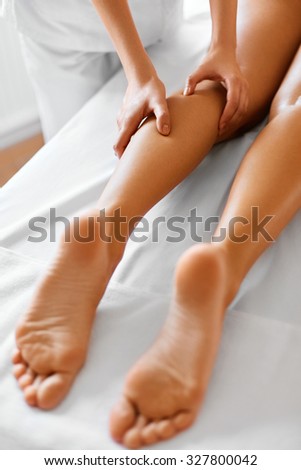 Spa woman. Body care. Close-up of beautiful long tanned woman legs receiving massage in spa salon. Body care, skin care, wellbeing, wellness concept. Anti-cellulite spa treatment.