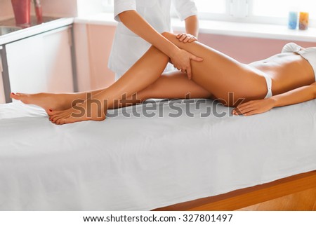 Spa treatment. Body care. Massage of human legs in spa salon.Close-up of masseur applying moisturizing oil and massaging beautiful long tanned female legs. Skin care, wellness concept.