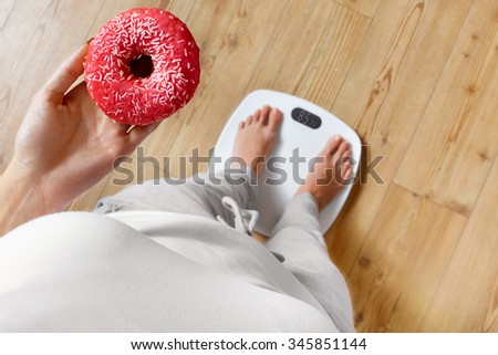 Diet. Woman Measuring Body Weight On Weighing Scale Holding Donut. Sweets Are Unhealthy Junk Food. Dieting, Healthy Eating, Lifestyle. Weight Loss. Obesity. Top View