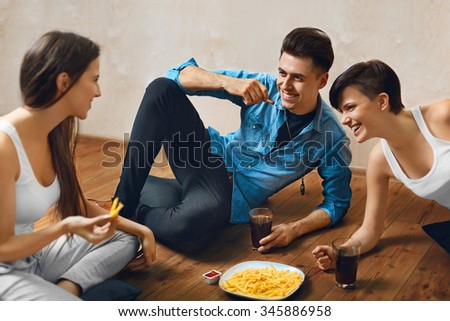 Eating Food. Group Of Happy Young Friends Eating Fast Food ( French Fries ) And Drinking Cold Soda While Sitting On The Floor At Home.  Celebration, Friendship, Leisure, People Concept